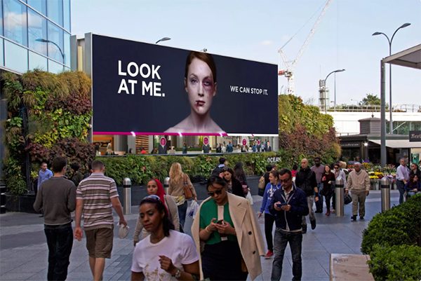 Interactive billboard shows a bruised woman with the caption, "Look at me. We can stop this."